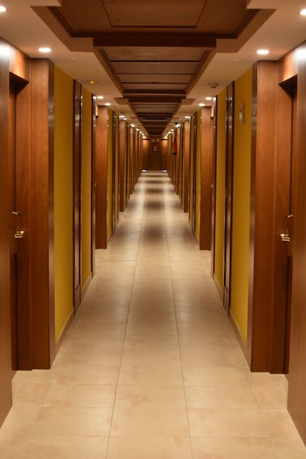 Long hallway view of a modern hotel with wooden doors and ceiling, creating a luxurious ambiance.